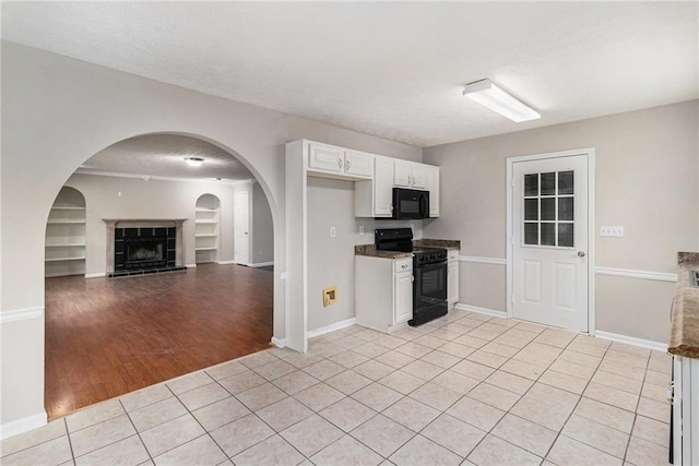 kitchen with built in features, white cabinetry, baseboards, light tile patterned floors, and black appliances