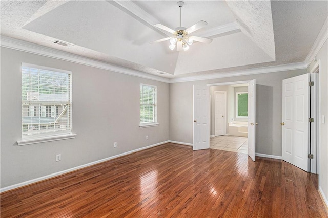 unfurnished bedroom featuring a textured ceiling, visible vents, a raised ceiling, and hardwood / wood-style floors