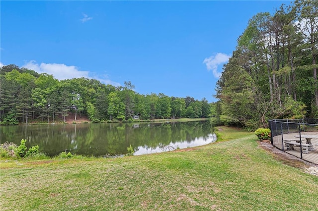 water view featuring fence and a wooded view