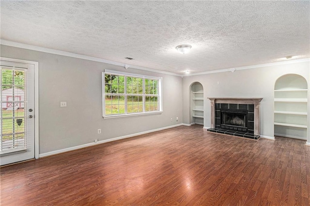 unfurnished living room with crown molding, wood finished floors, a healthy amount of sunlight, a textured ceiling, and built in shelves