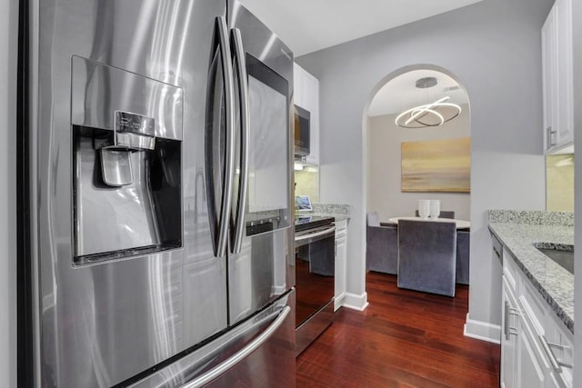 325 E Paces Ferry Rd NE Unit 1910, Atlanta, GA 30305 - kitchen featuring appliances with stainless steel finishes, dark wood-type flooring, arched walkways, white cabinetry, and light stone countertops