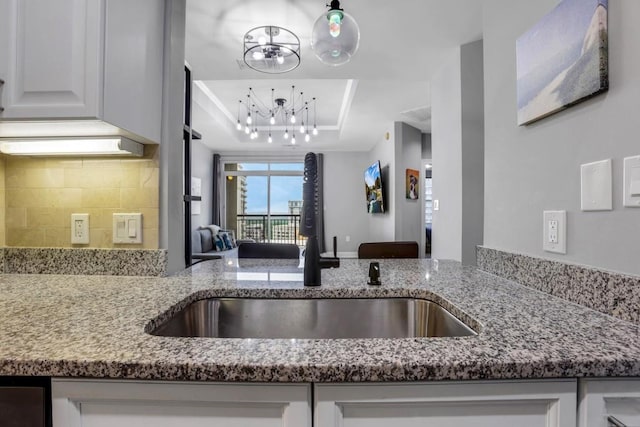325 E Paces Ferry Rd NE Unit 1910, Atlanta, GA 30305 - kitchen with a raised ceiling, light stone counters, a chandelier, and decorative backsplash
