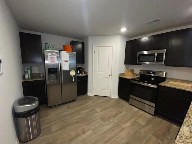 kitchen with light stone counters, light hardwood / wood-style flooring, and stainless steel appliances