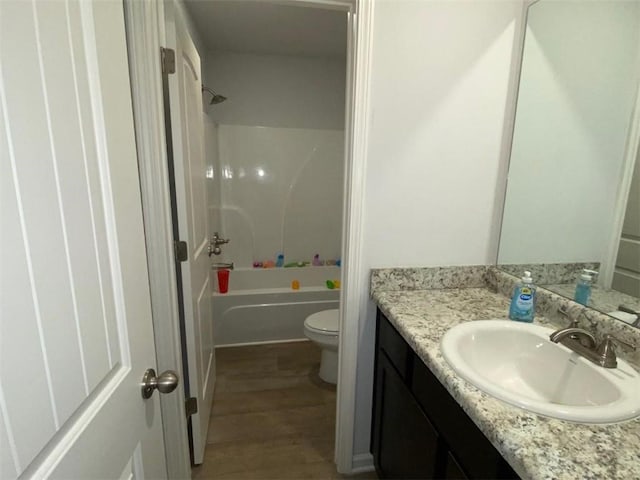 full bathroom with hardwood / wood-style floors, vanity, toilet, and washtub / shower combination