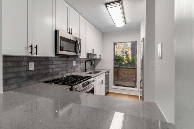 kitchen featuring a sink, tasteful backsplash, appliances with stainless steel finishes, and white cabinetry