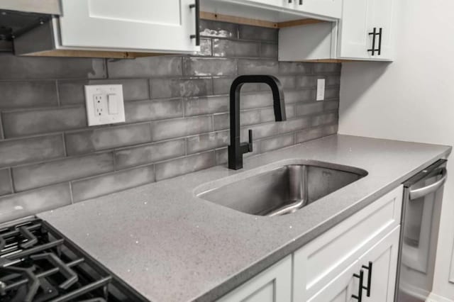 kitchen featuring light stone counters, white cabinetry, a sink, dishwasher, and tasteful backsplash