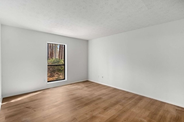 spare room featuring a textured ceiling, baseboards, and wood finished floors