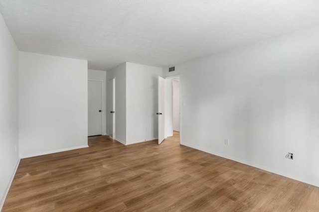 empty room featuring visible vents, baseboards, and wood finished floors