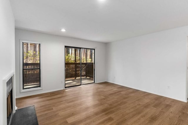 unfurnished living room featuring a fireplace with flush hearth, wood finished floors, and recessed lighting