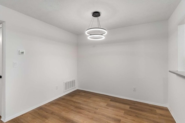 unfurnished dining area featuring visible vents, baseboards, and wood finished floors