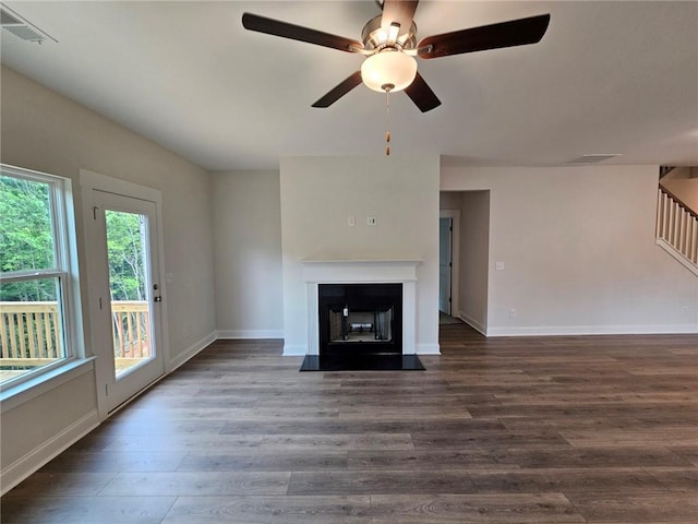 unfurnished living room featuring a healthy amount of sunlight, ceiling fan, and dark hardwood / wood-style flooring