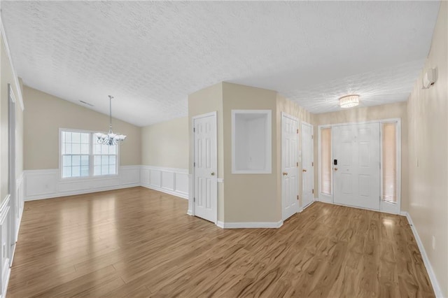 70 Prince Edward Way, Covington, GA 30016 - entrance foyer featuring a chandelier, a textured ceiling, wood finished floors, wainscoting, and vaulted ceiling