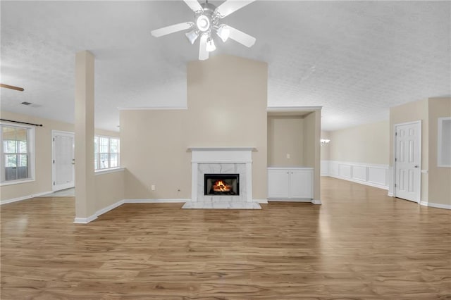 70 Prince Edward Way, Covington, GA 30016 - unfurnished living room featuring ceiling fan, light wood-style floors, a fireplace, a textured ceiling, and wainscoting