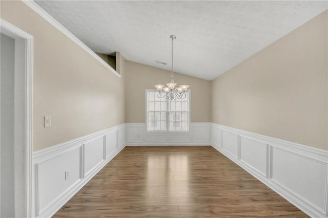 70 Prince Edward Way, Covington, GA 30016 - unfurnished dining area with a chandelier, vaulted ceiling, wood finished floors, wainscoting, and a textured ceiling
