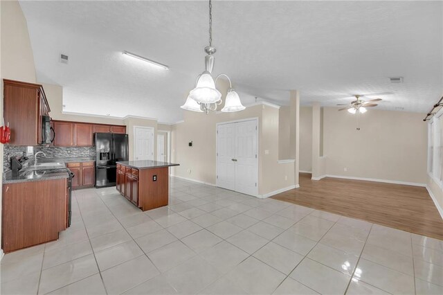 70 Prince Edward Way, Covington, GA 30016 - kitchen with light tile patterned floors, a chandelier, a kitchen island, hanging light fixtures, and vaulted ceiling