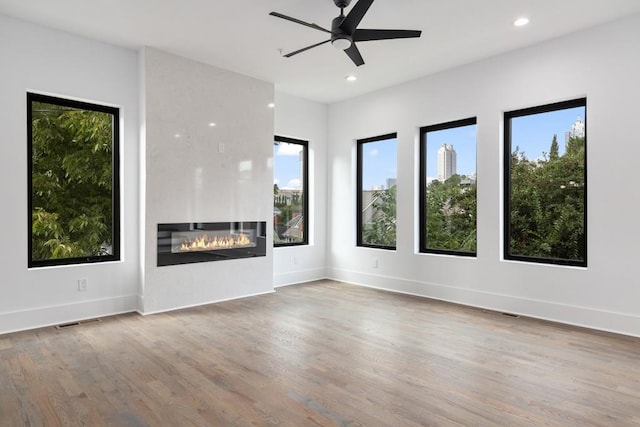unfurnished living room with recessed lighting, visible vents, a healthy amount of sunlight, and wood finished floors