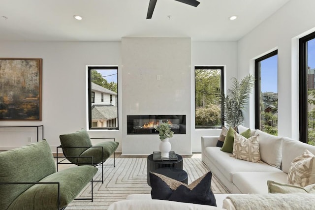living area featuring recessed lighting, ceiling fan, a large fireplace, and wood finished floors