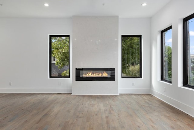 unfurnished living room with recessed lighting, wood finished floors, and a wealth of natural light