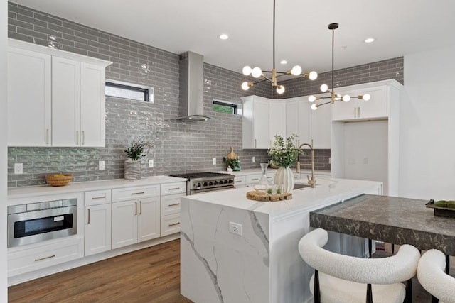 kitchen with tasteful backsplash, a sink, white cabinets, wall chimney exhaust hood, and dark wood-type flooring