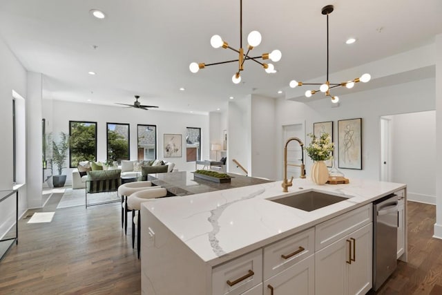 kitchen featuring stainless steel dishwasher, recessed lighting, white cabinets, a sink, and decorative light fixtures