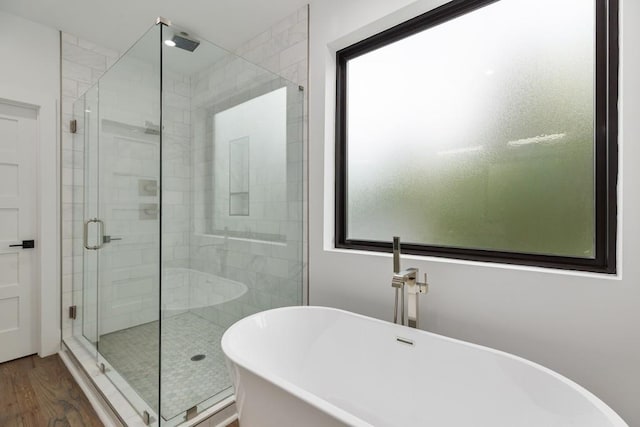bathroom with wood finished floors, a soaking tub, and a stall shower