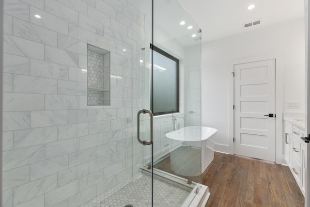 bathroom with recessed lighting, a freestanding tub, wood finished floors, visible vents, and a stall shower