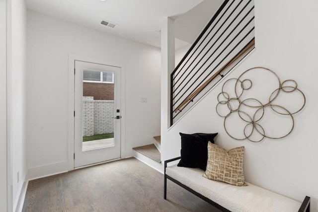 foyer with baseboards, visible vents, wood finished floors, and stairway