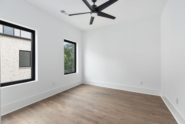empty room with a ceiling fan, baseboards, visible vents, and wood finished floors