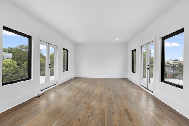 empty room featuring french doors, recessed lighting, baseboards, and wood finished floors