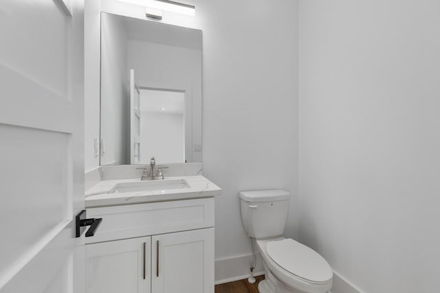 bathroom with vanity, baseboards, and toilet
