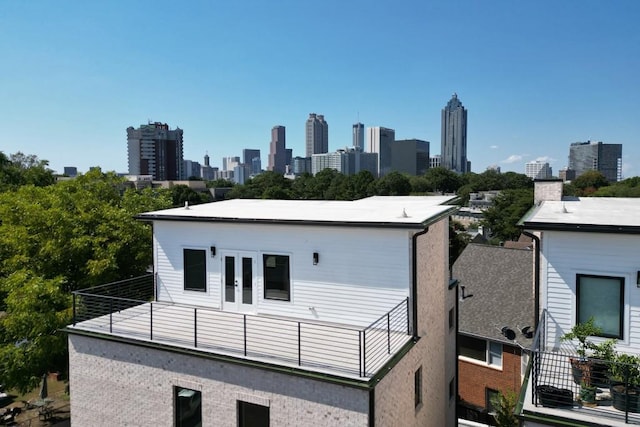 back of property with brick siding, a view of city, french doors, and a balcony