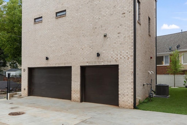 view of home's exterior featuring brick siding, a garage, central AC unit, and concrete driveway