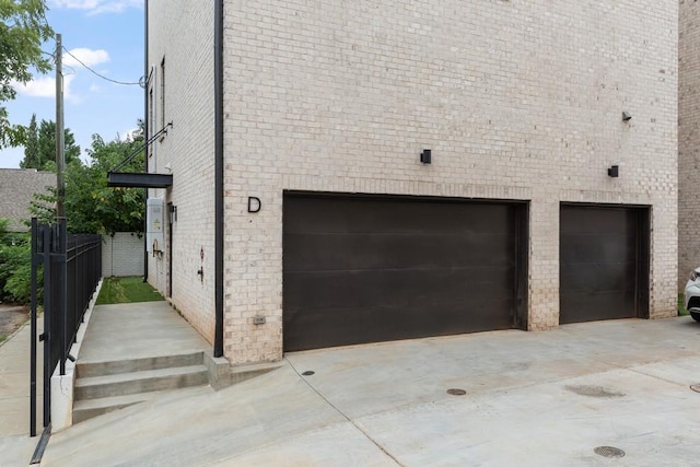 view of side of property featuring an attached garage, driveway, and brick siding