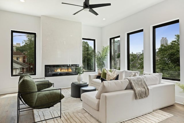 living area with a ceiling fan, recessed lighting, wood finished floors, and a fireplace
