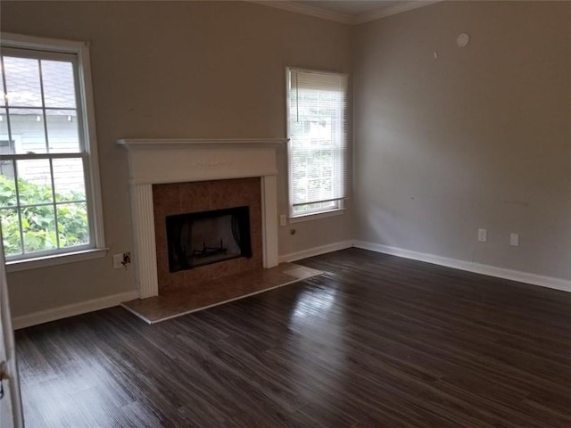 unfurnished living room featuring a tiled fireplace, dark wood finished floors, baseboards, and ornamental molding