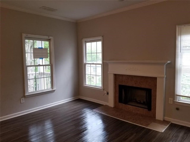 unfurnished living room featuring visible vents, ornamental molding, dark wood-style floors, baseboards, and a tile fireplace