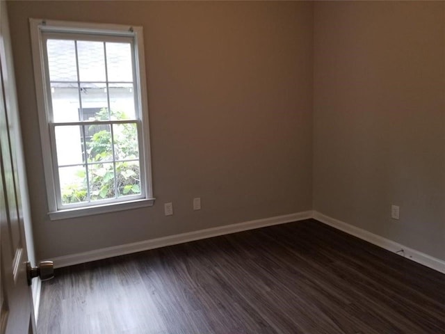 spare room with baseboards and dark wood-style flooring