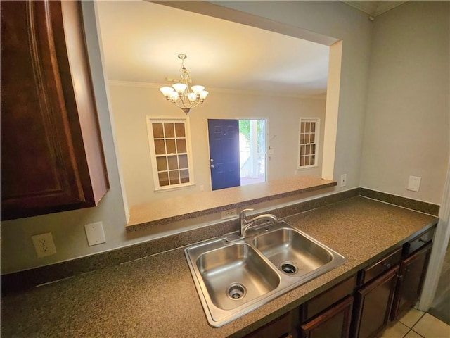 kitchen featuring dark countertops, decorative light fixtures, ornamental molding, and a sink