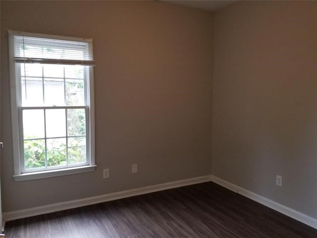 empty room featuring dark wood finished floors and baseboards