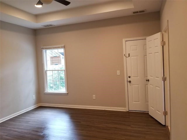 unfurnished room with visible vents, baseboards, and dark wood-style flooring