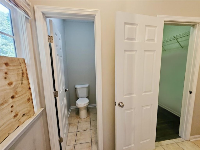 bathroom with tile patterned floors, baseboards, and toilet