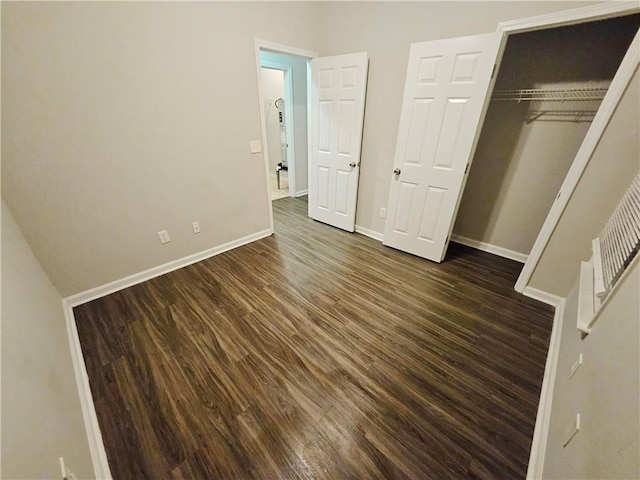 unfurnished bedroom featuring a closet, dark wood-type flooring, and baseboards