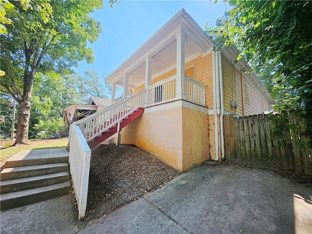 view of side of home featuring stairs and fence