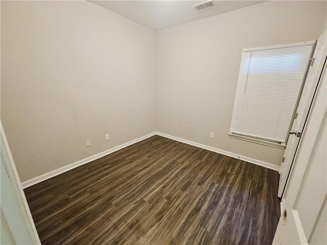 unfurnished room with dark wood-style floors, visible vents, and baseboards