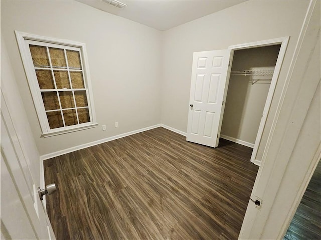 unfurnished bedroom featuring a closet, visible vents, dark wood-type flooring, and baseboards