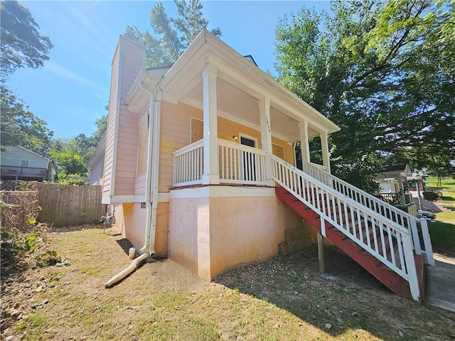 view of front of home with stairway, a porch, a chimney, and fence