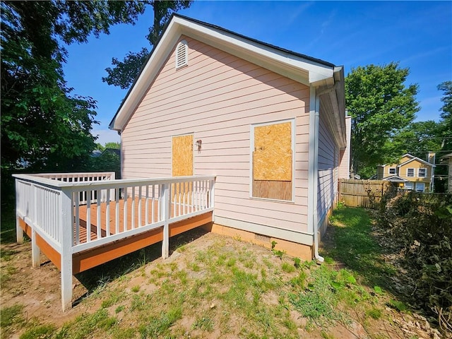 rear view of property with a wooden deck, fence, and crawl space