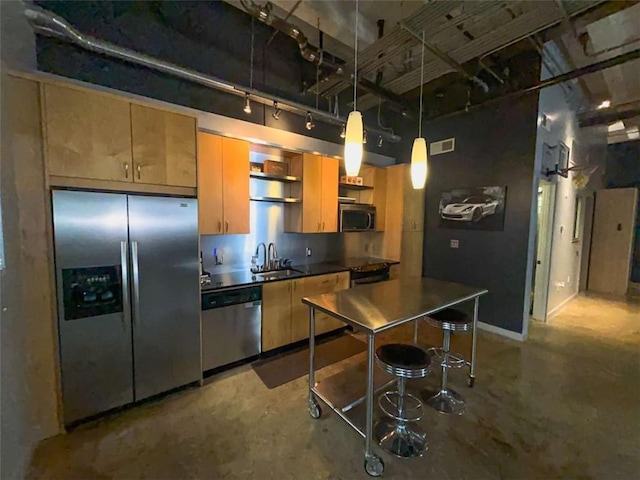 kitchen with sink, stainless steel appliances, concrete floors, decorative light fixtures, and a kitchen bar