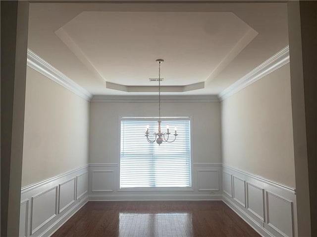 unfurnished dining area featuring a notable chandelier, a raised ceiling, ornamental molding, and dark wood-type flooring