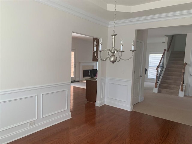 unfurnished dining area featuring crown molding, dark wood-type flooring, and a notable chandelier